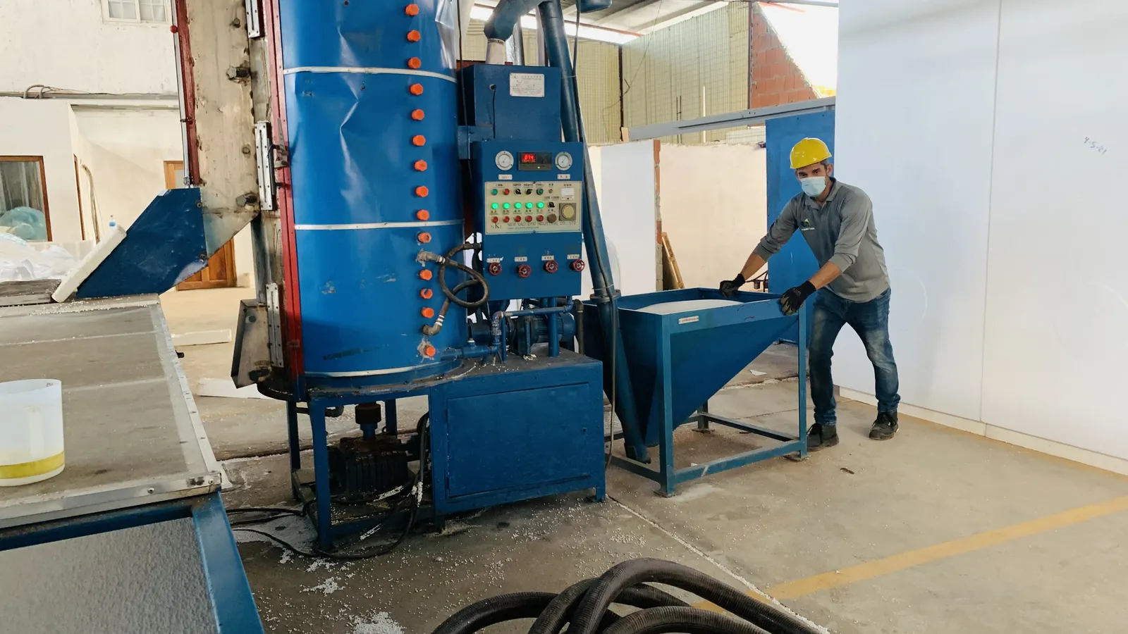 Operario de Azuero Panel con casco junto al pre-expansor de EPS